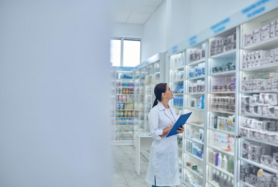 a woman in a white coat holding a clipboard in a pharmacy