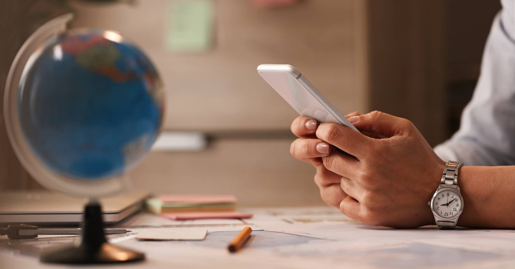 The Ultimate Strategic Guide to Conquering Global Markets: How to Choose a Retail Translation Services Partner. person cheching smartphone withe glob model
