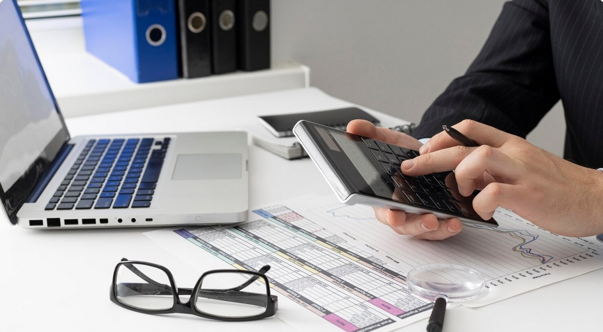 a man using a calculator while working with a laptop