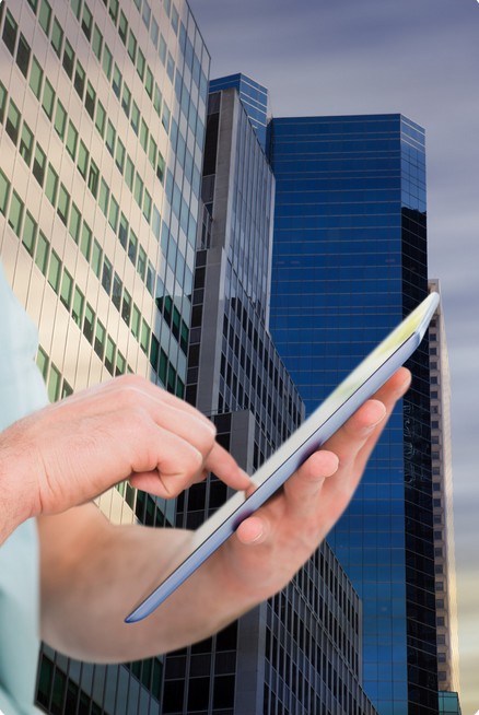 a man checking information at a tablet in fornt of a skyscraper