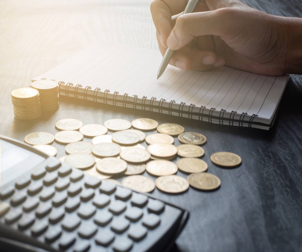 image showing coins, calculator and a person writing