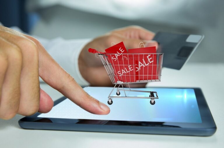 conceptual image showing a person touching a smartphone screen with shoping cart on it